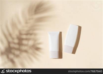 Minimal modern cosmetic scene with two tubes on beige background with shadow overlay. Minimal product display