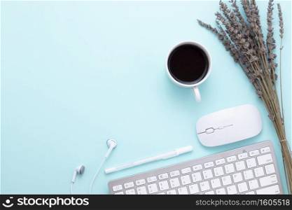 Minimal Office desk table with Keyboard computer, coffee cup, mouse, white pen, Earphones, lavender flowers on a green table with copy space for input your text, green color workplace composition, flat lay, top view