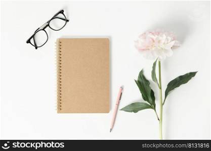 Minimal styled flat lay with peony flower and blank notebook. Mock up top view on white background