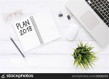 Minimal work space - Creative flat lay photo of workspace desk with Plan 2018 New Year list notebook and laptop on wooden background. Top view flat lay photography. 2018 happy new year concept.