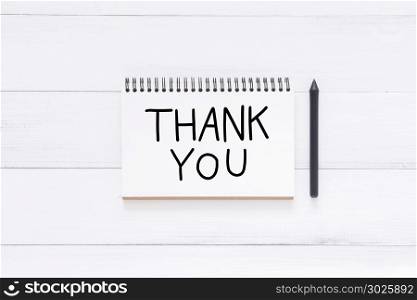 Minimal workspace - Flat lay view photo of word thank you caligraphy note in a notebook siding with pen on white wooden background. Top View flat lay photography. New year 2018 thank you concept