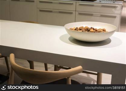 Minimalist Kitchen with Clean Surfaces and Bowl of Nuts on Table and Wooden Chair