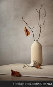 Minimalist monochrome still life composition with ceramic vase and autumn branch in beige color, abstract modern art design concept, copy space
