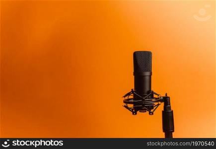 Minimalistic image of a streaming microphone over an orange background with copy space, minimal concept, technology streaming