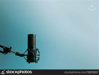 Minimalistic image of a streaming microphone over an pastel blue background with copy space, minimal concept, technology streaming