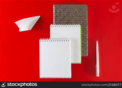 Minimalistic layout for design. Office supplies - notebooks and pens on a red background.