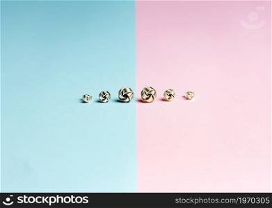 Minimalistic shot of a group of earrings over a pastel pink and blue background