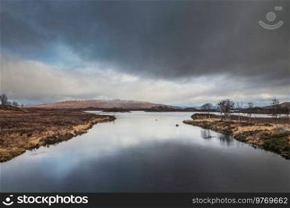 Minimalistic Winter landscape across Loch Ba in Rannoch Moor with stormy dramatic sky overhead