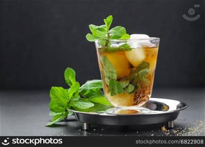 Mint Julep cocktail with bourbon, ice and mint in glass on black background