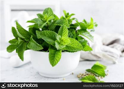 Mint leaves in bunch on white kitchen table closeup