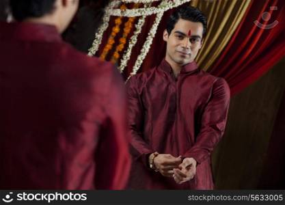 Mirror reflection of young Indian bridegroom getting dressed
