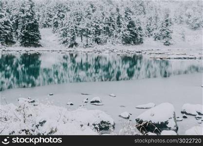 Mirror surface of the winter lake with a mountain range. First snow in the mountains. Travel to the national Park in the Altai mountains.