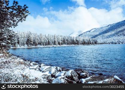 Mirror surface of the winter lake with a mountain range. First snow in the mountains. Travel to the national Park in the Altai mountains.