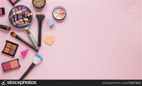 Mirror with eye shadows and powder brushes on pink table