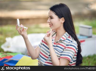 Mirror woman Make up cosmetics / Beautiful smiling young girl make up face powder personally on park outdoors