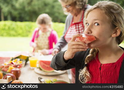 Mischievous girl at patio table eating watermelon slice