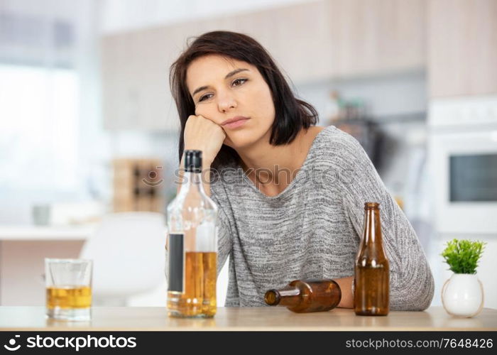 miserable young drunk woman sat at table at home