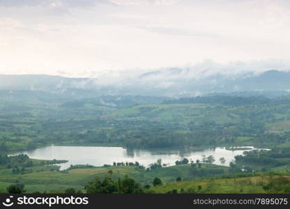 Mist covered mountains and farmland. In the evening, a cold and is nearly dark.