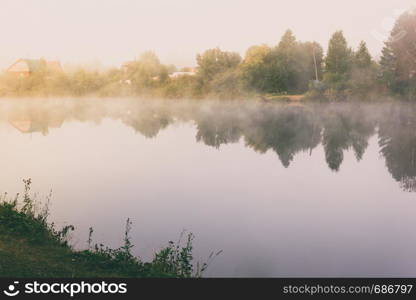 Misty morning on river. Trees on lake. Mysterious fishing pond