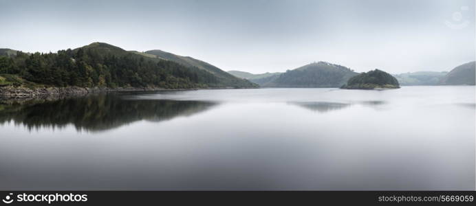 Misty morning panorama landscape over calm lake in Autumn