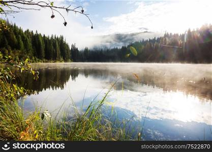 Misty mountain lake in the early serene morning in mountains.