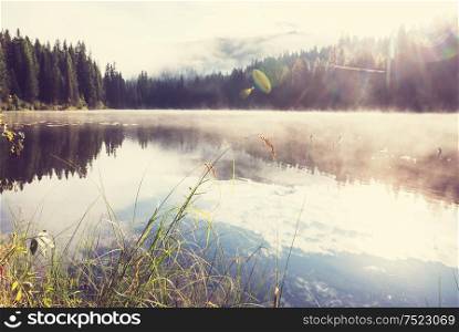 Misty mountain lake in the early serene morning in mountains.