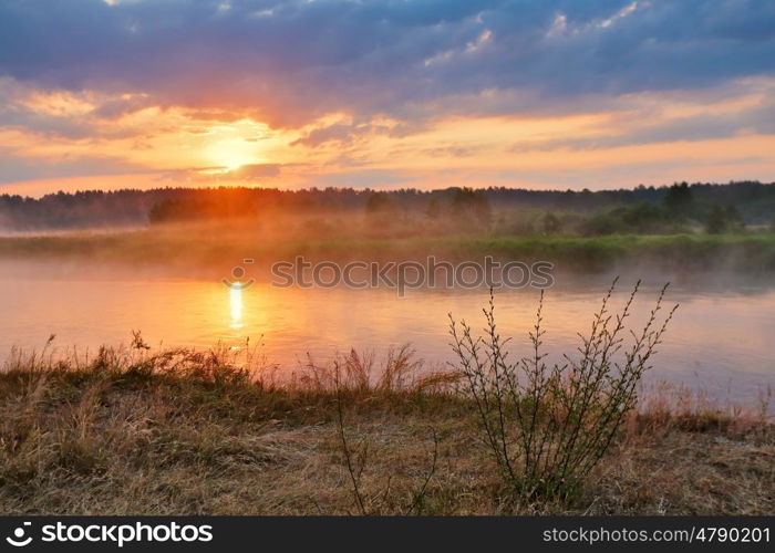 Misty summer sunrise. Foggy river in the morning. Colorful summer morning. Dirt road at summer morning riverbank