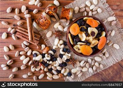 Mix of dried fruits in a wooden bowl and nuts over a rustic table seen from above. Mix of dried fruits and nuts seen from above