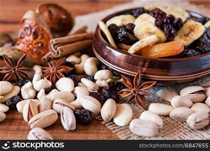 Mix of dried fruits in a wooden bowl and nuts over a rustic table. Mix of dried fruits and nuts