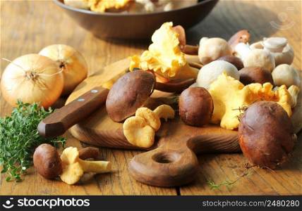 Mix of forest mushrooms on cutting board over old wooden table .. Mix of forest mushrooms on cutting board over old wooden table