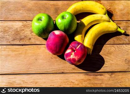 Mix of fruits on wooden table. Banana, apple, nectarine