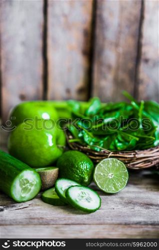 Mix of green fruits and vegetables on rustic wooden background
