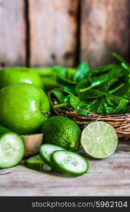 Mix of green fruits and vegetables on rustic wooden background