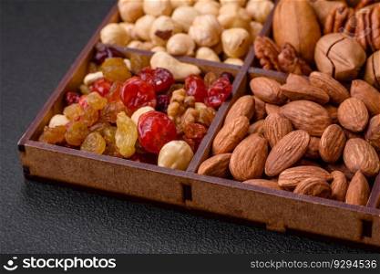 Mix of roasted macadamia nuts, cashews, pecans, almonds, raisins and dry berries on a dark concrete background