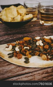 Mix of snacks with chips, nuts, seeds and beer