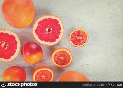 Mix of whole and cut citruses with copy space on white wooden table, retro toned. Variety of citruses