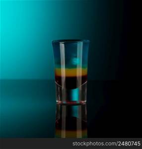 mixed alcoholic liquor in a shot glass isolated on a dark background with backlighting. shot glass with alcohol on a dark background