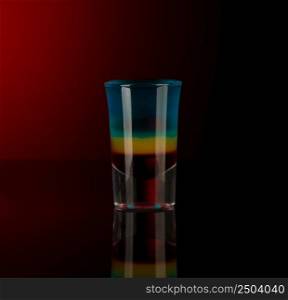 mixed alcoholic liquor in a shot glass isolated on a red background with backlighting. shot glass with alcohol on a dark background