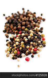 Mixed assorted peppercorns on white background macro