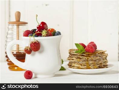 Mixed berries and Stack of pancakes topped with berries and honey