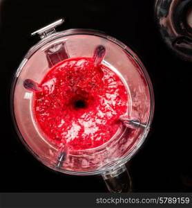 Mixed berries in a blender viewed from the top as they are being liquidized.