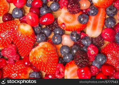 Mixed berries viewed from above as they lie spread out on a bamboo cutting board.