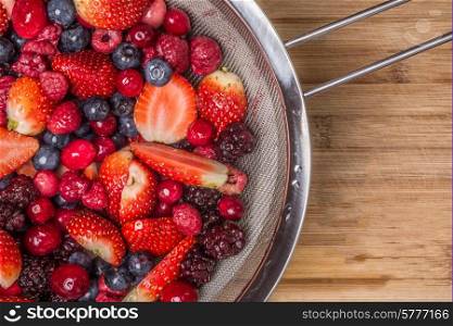 Mixed berries viewed from above as they lie spread out on a bamboo cutting board.