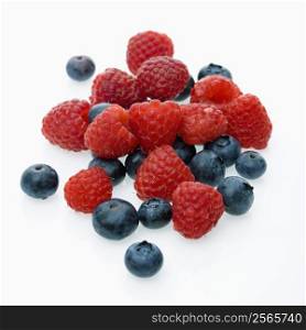 Mixed blueberries and raspberries on white background.