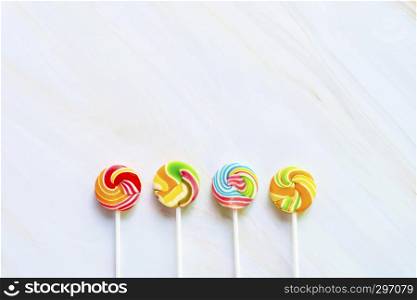 Mixed colorful lollipops on white marble table with free copy space background. Childhood and happiness.