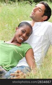 Mixed couple laying in a field