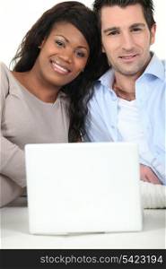Mixed couple sat with laptop