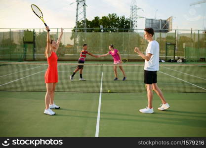 Mixed doubles tennis, players finished the game, outdoor court. Active healthy lifestyle, sport with racket and ball, fitness workout with racquets. Mixed doubles tennis, players finished the game