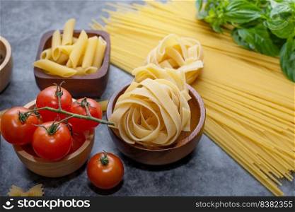 Mixed dried pasta selection on wooden background. composition of healthy food ingredients isolated on black stone background, top view, Flat lay