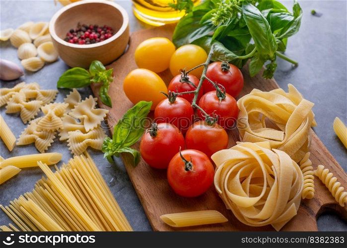 Mixed dried pasta selection on wooden background. composition of healthy food ingredients isolated on black stone background, top view, Flat lay